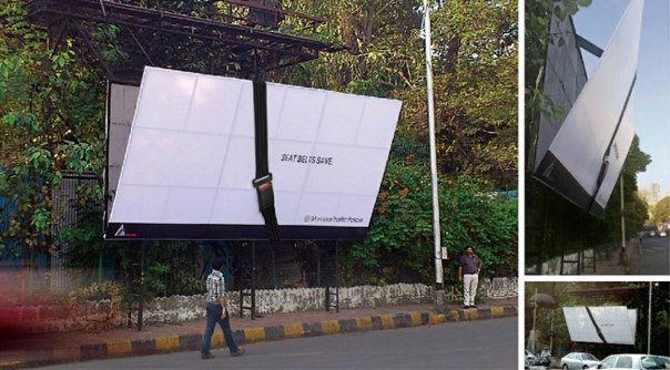 Социальная реклама на наклоненном бигборде, который держится на ремне безопасности: "Ремни безопасности спасают"